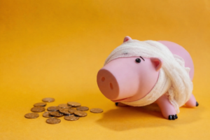 A piggy bank wrapped in a bandage next to a pile of coins, symbolizing the impact of financial mistakes on retirement savings.